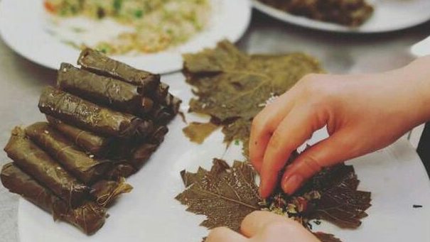 Le mani di una cuoca mentre prepara dei tipici involtini siriani